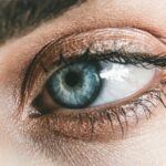 Detailed close-up of a woman's blue eye, showcasing makeup and eyelashes.